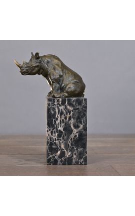 Escultura bronceada de un rinoceronte en una base de mármol negro